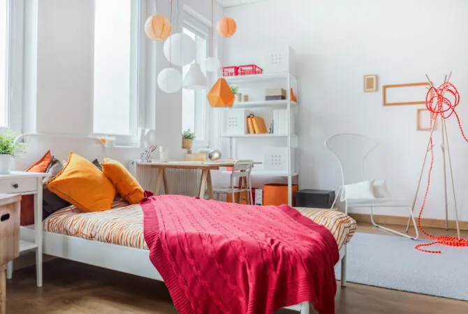 Decorated dorm room with small twin size bed and small office desk.