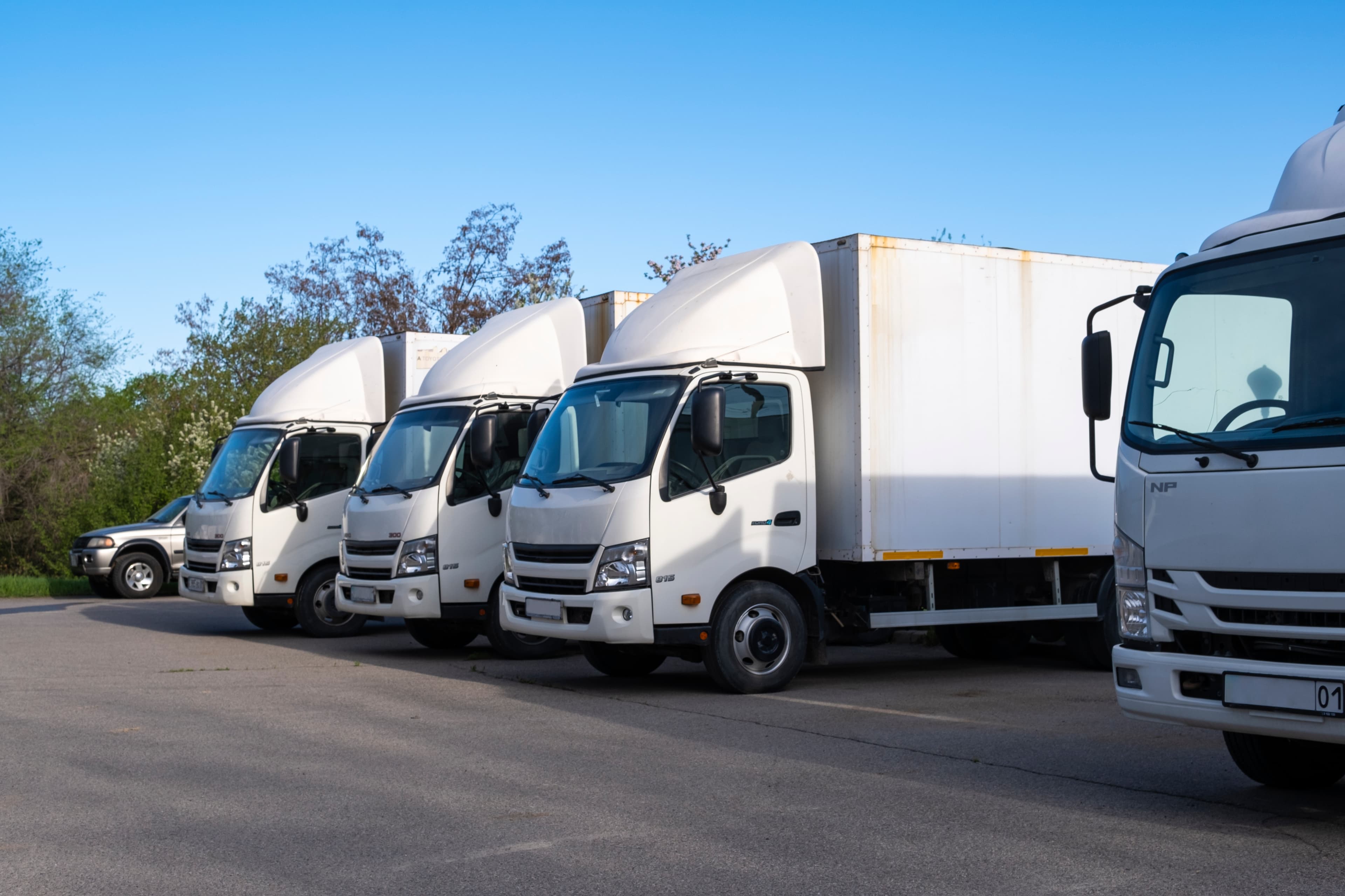 Four large business trucks parked at a storage facility