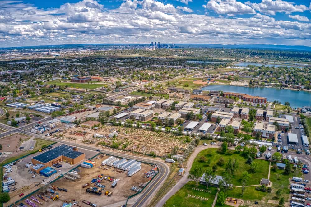 Aerial view of Westminster, CO, showing suburban neighborhoods, commercial areas, and nearby lakes with the Denver skyline in the distance.
