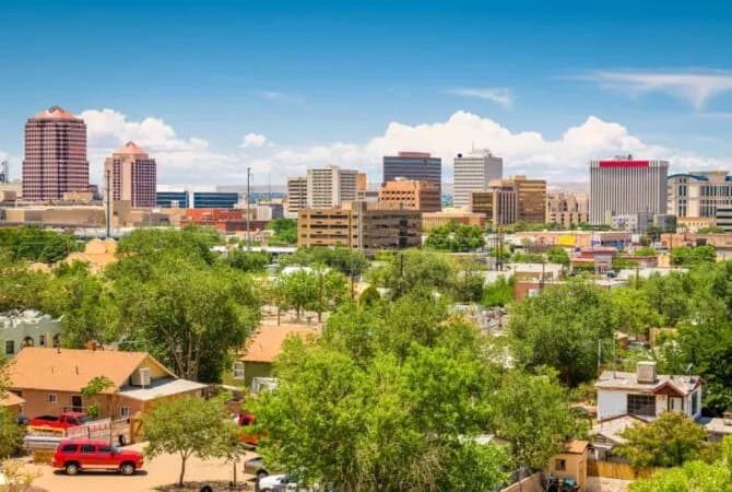 Albuquerque skyline on summer day with houses and trees in foreground and taller buildings in background