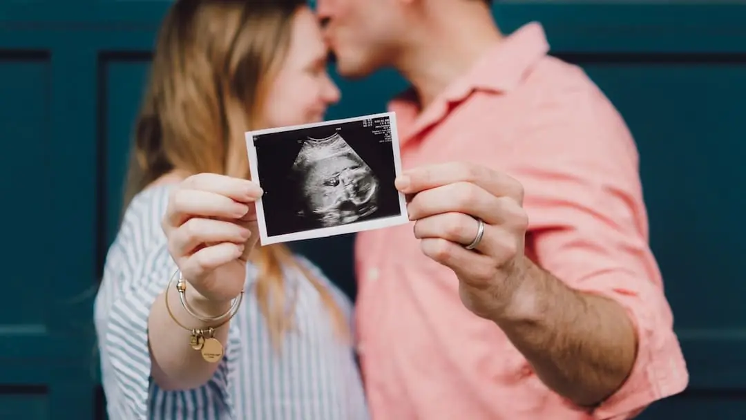 A couple holding an ultrasound of a baby.