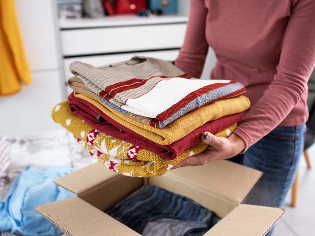 Holding folded clothes above a box