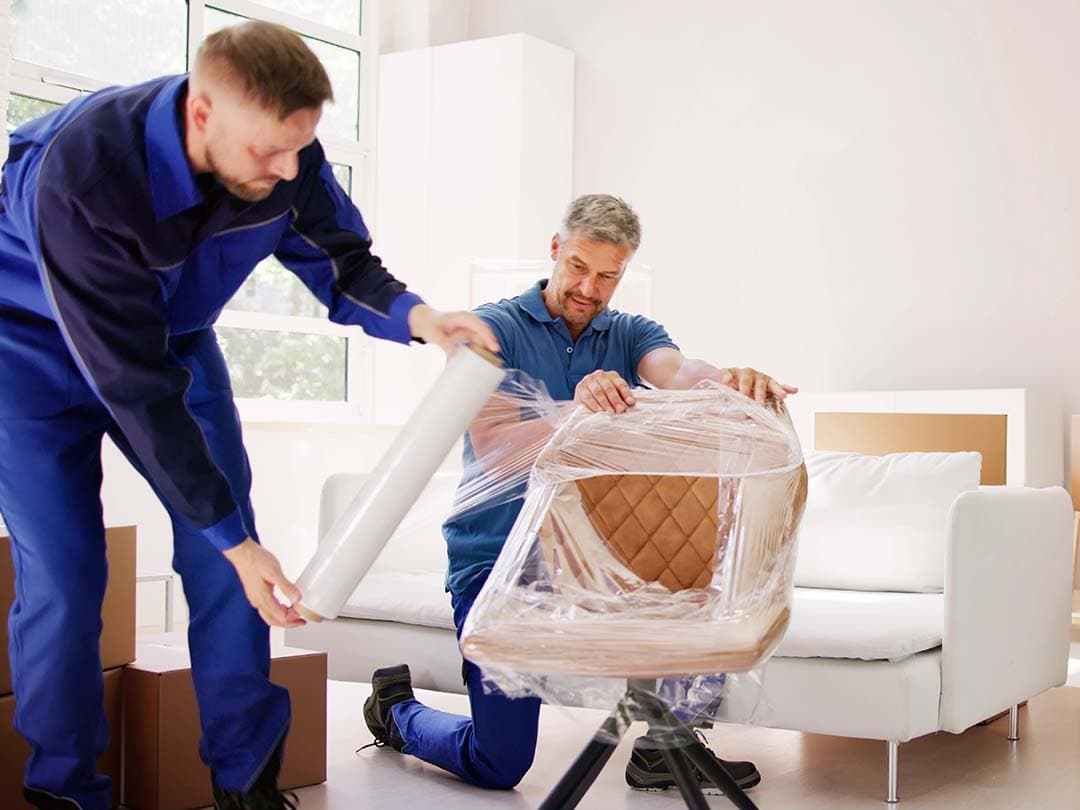Two movers wrapping a chair