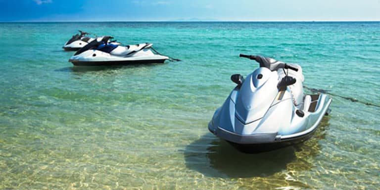 three jet skis anchored in ocean water near the beach