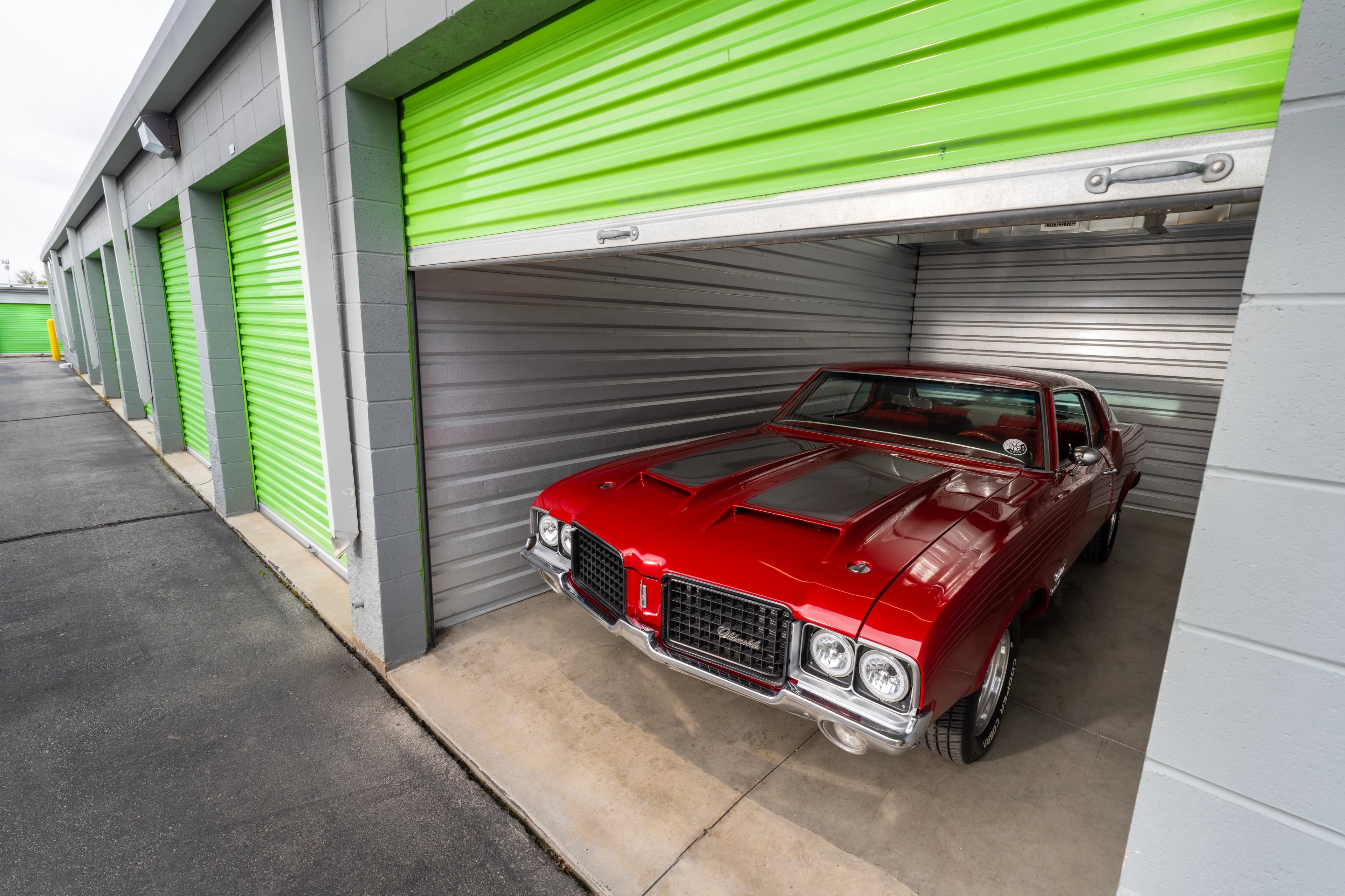 A nice red car inside of a green storage unit.