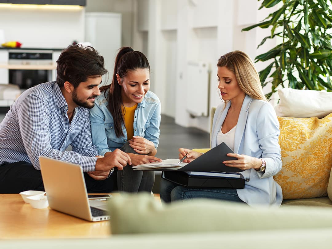 3 people sitting down looking at a booklet discussing items
