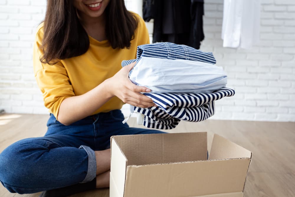 Woman packing clothes into moving boxes.
