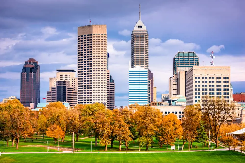 Indianapolis skyline with tall skyscrapers and trees blooming for fall during dark, stormy day