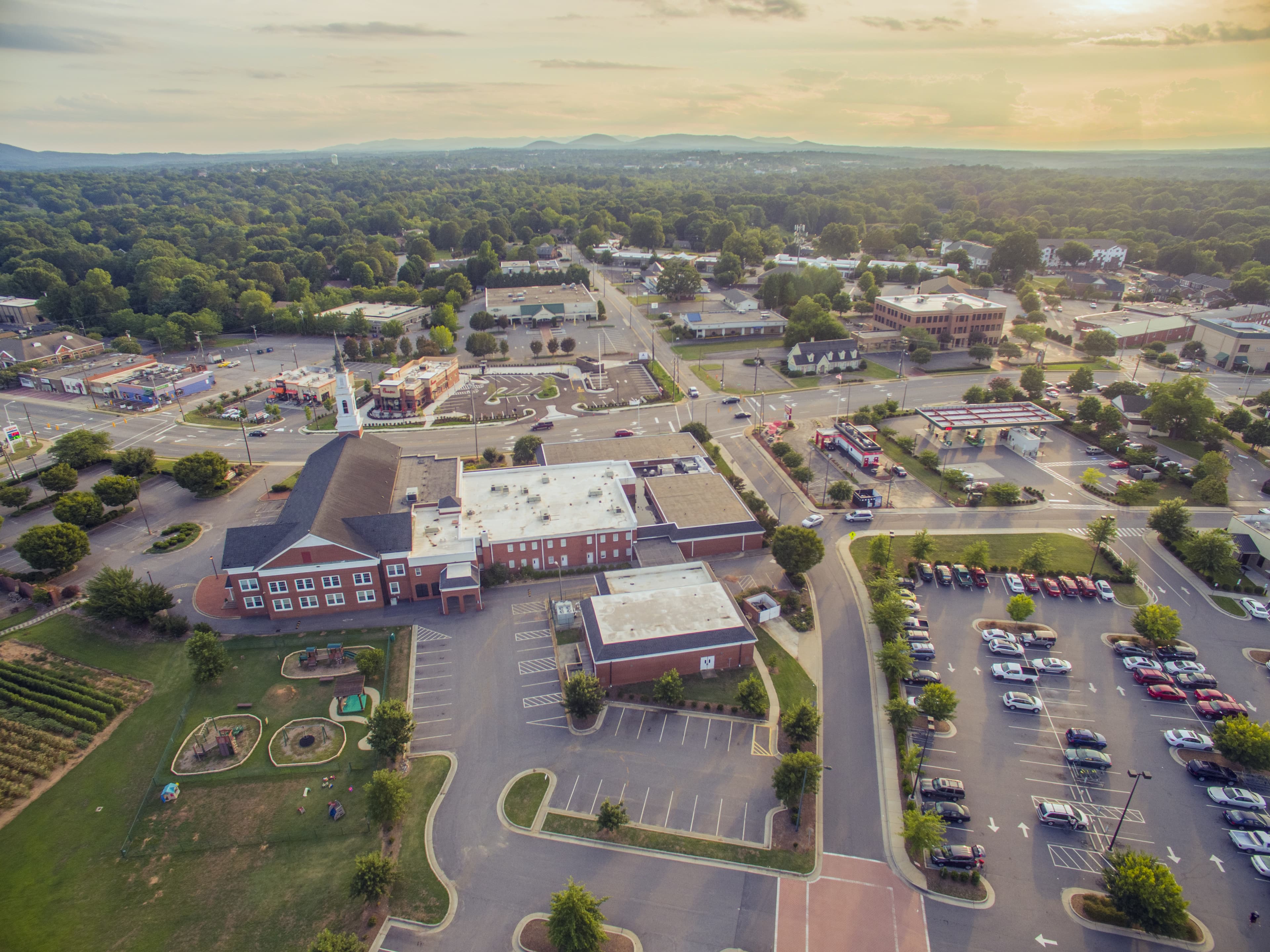 Aerial image of Hickory, NC during dusk, featuring trees and mountains along the horizon.