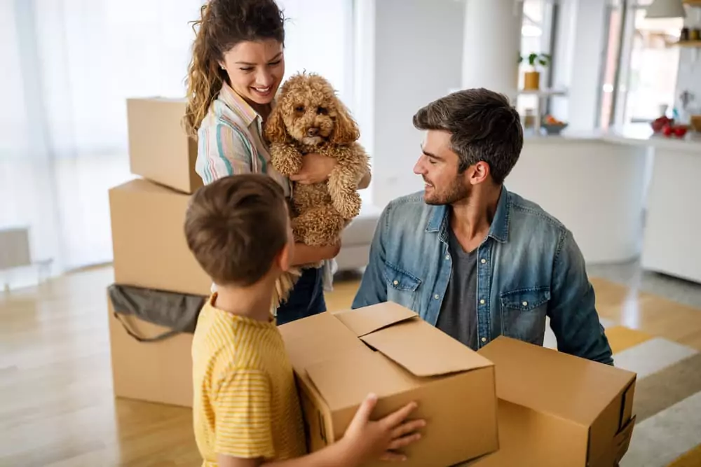 A family with moving boxes and a dog.
