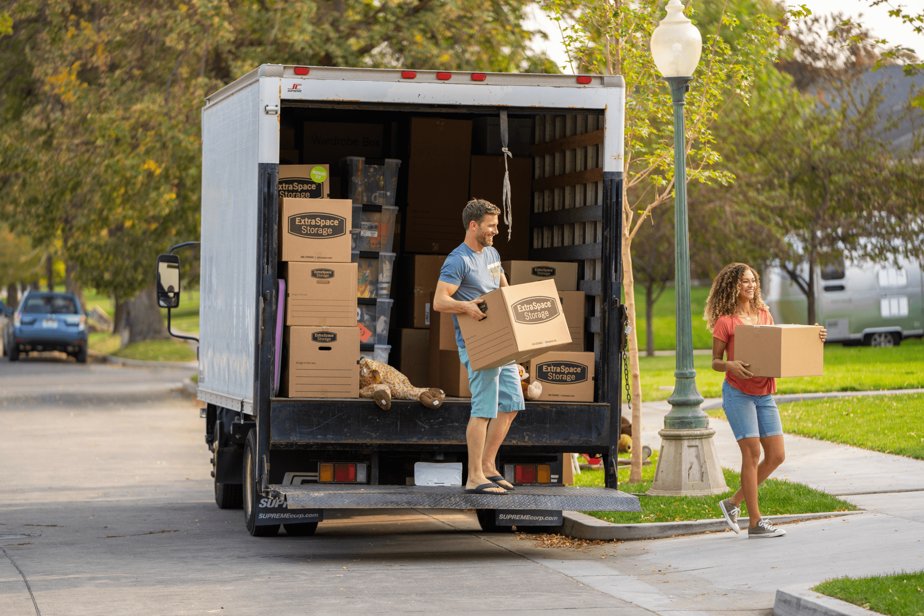 2 people carrying Extra Space Storage moving boxes out of a moving truck