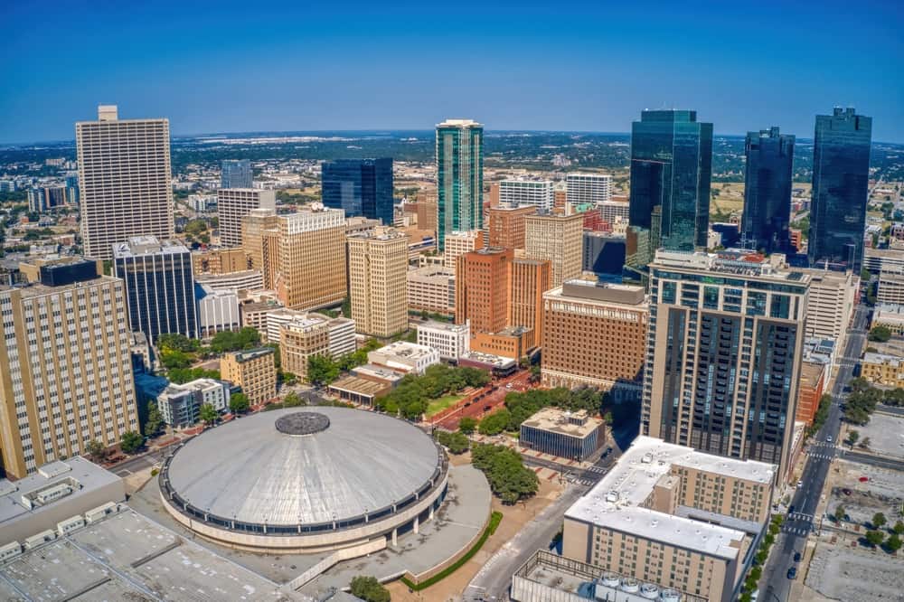 Fort Worth skyline, with multiple skyscrapers above smaller buildings, major streets, and a park on a sunny day.