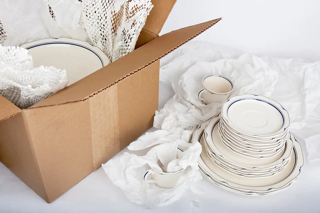 Dishes partially wrapped in tissue paper and packed in a cardboard box for moving or storage