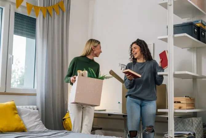Two college female college students moving into a dorm room.