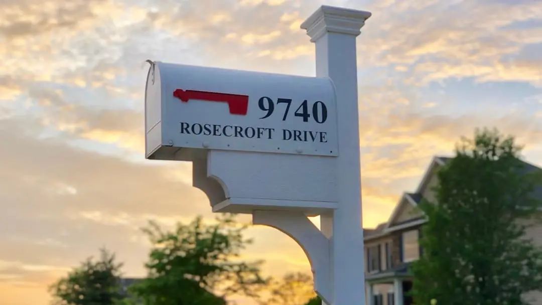 A mailbox in front of a house at sunset