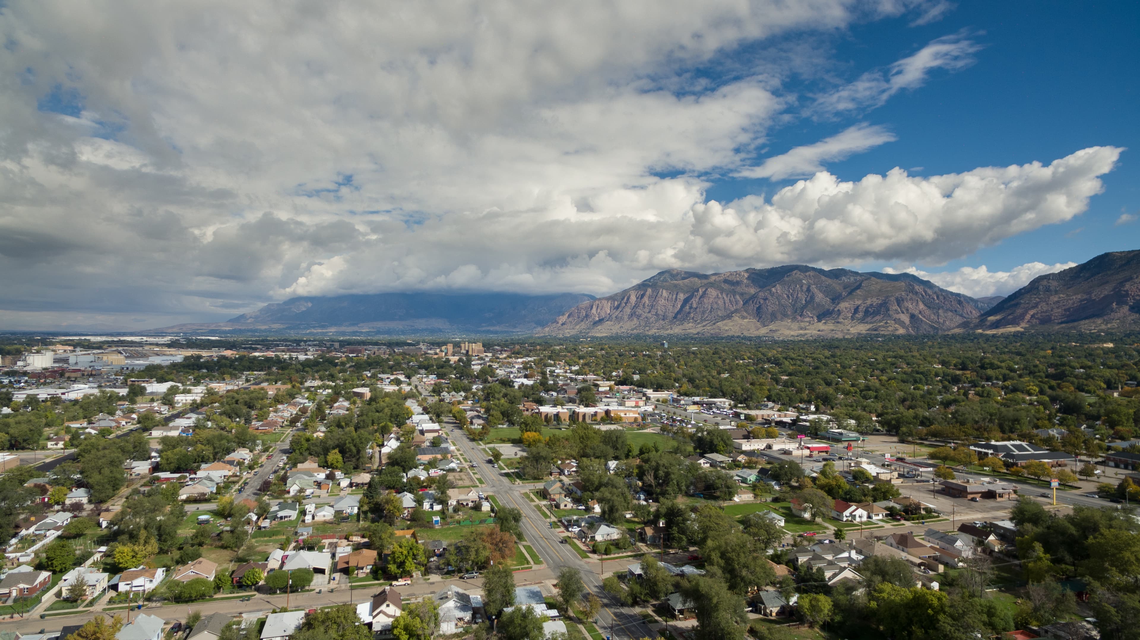 Skyline image of Ogden, UT with clouds and mountains.