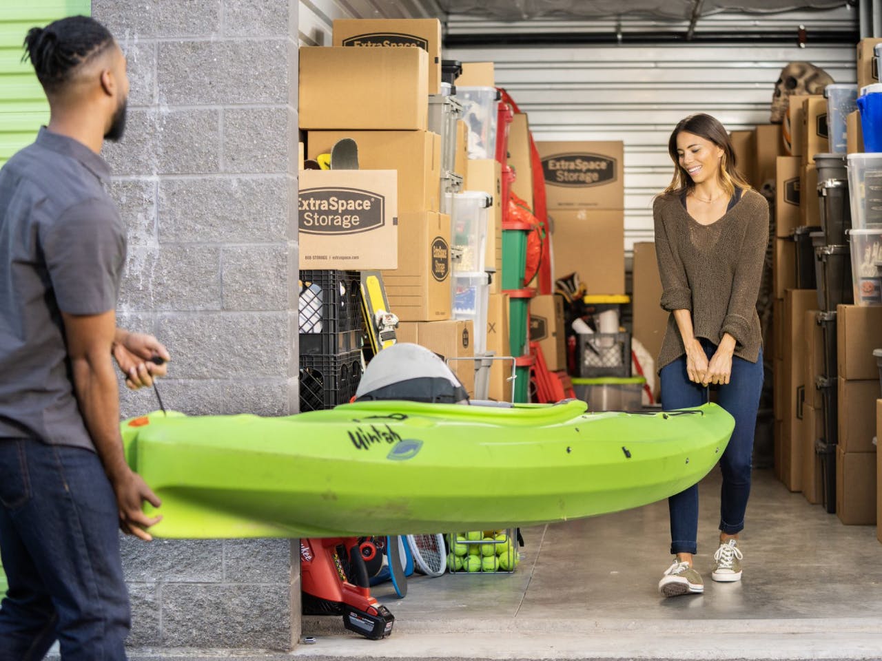 Couple moving kayak into a storage unit 