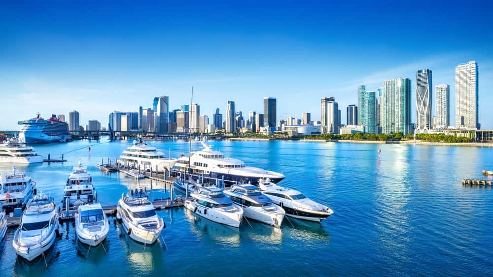 Harbor in Miami with ships in marina and Miami city skyline in background on clear day