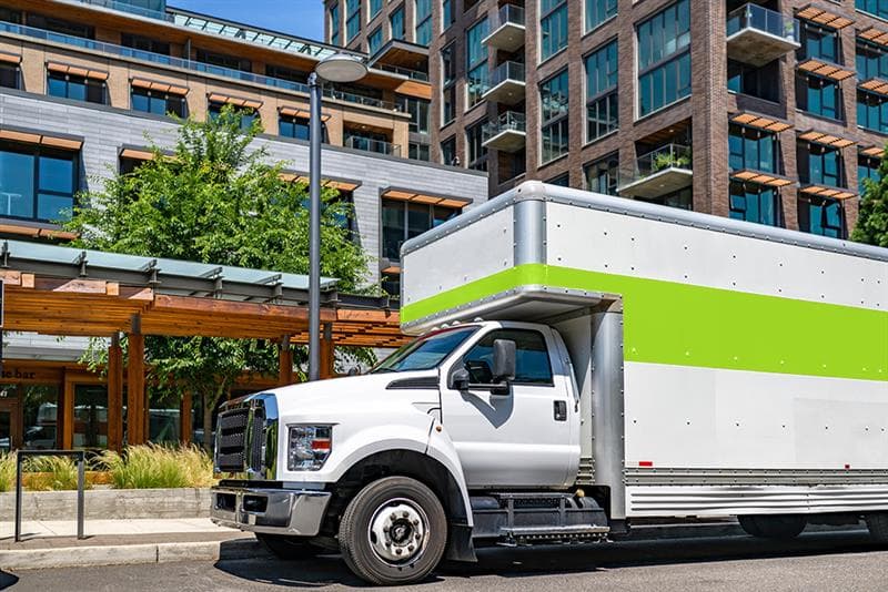 Moving truck parked on a street near buildings.