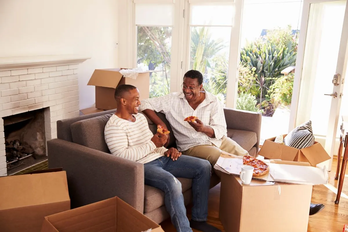 Two men talking on a couch around moving boxes
