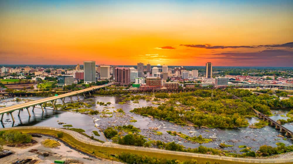 Richmond, VA city skyline at sunset with bridge over water and skyscrapers