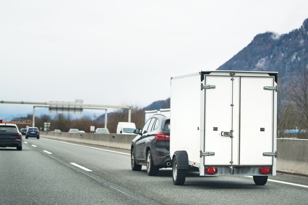 A car with a moving trailer on the highway.