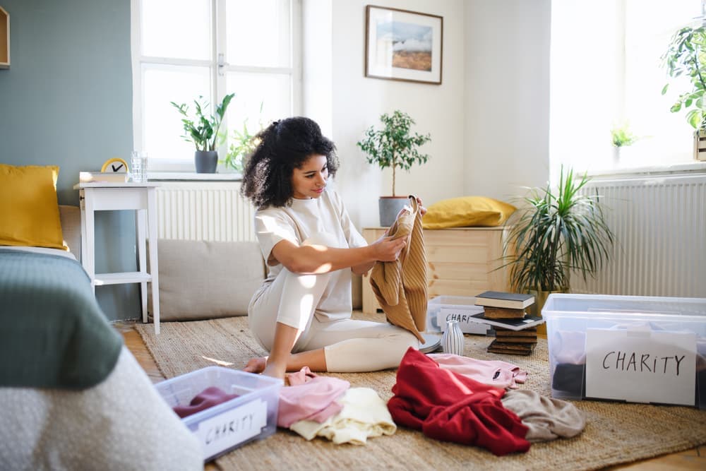 A woman sitting on the floor folding clothes