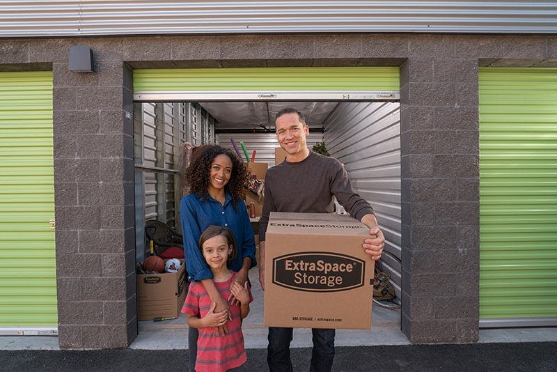 Family of three standing outside of a storage unit 