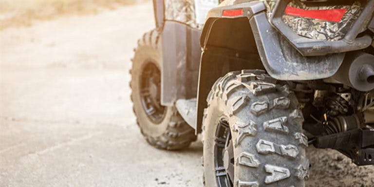 close up of four wheel ATV vehicle parked in a driveway