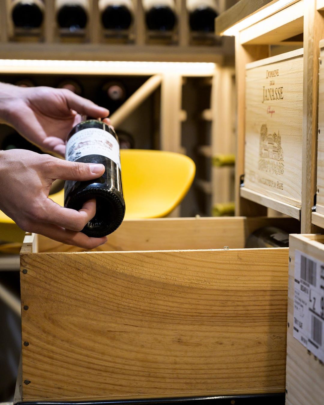 Hands putting wine bottle into wine storage box. Photo by Instagram user @sorrells_wineracks