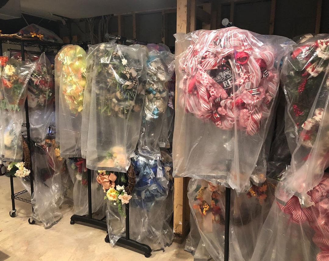 Garment bags over holiday wreaths. Photo by Instagram user @eventcraftstudio