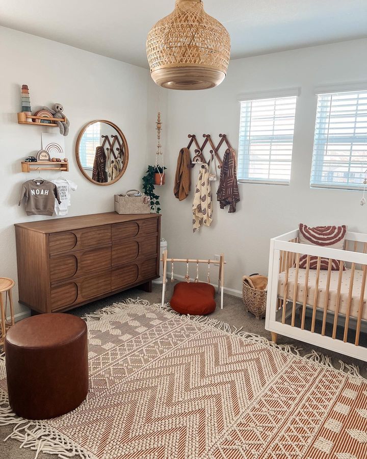 A well-lit baby room with compact baby furniture and striped rug on the floor. @sarahjean.lollis.
