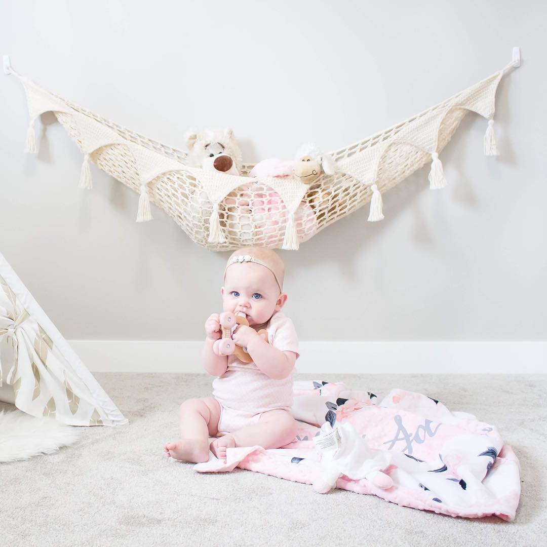 Baby sitting in front of hammock with baby toys. Photo by Instagram user @mamamadeitshop