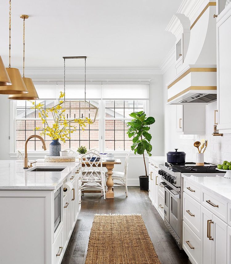 Galley view of a white and neutrally toned kitchen and dining room. Photo by Instagram user @rymcdon
