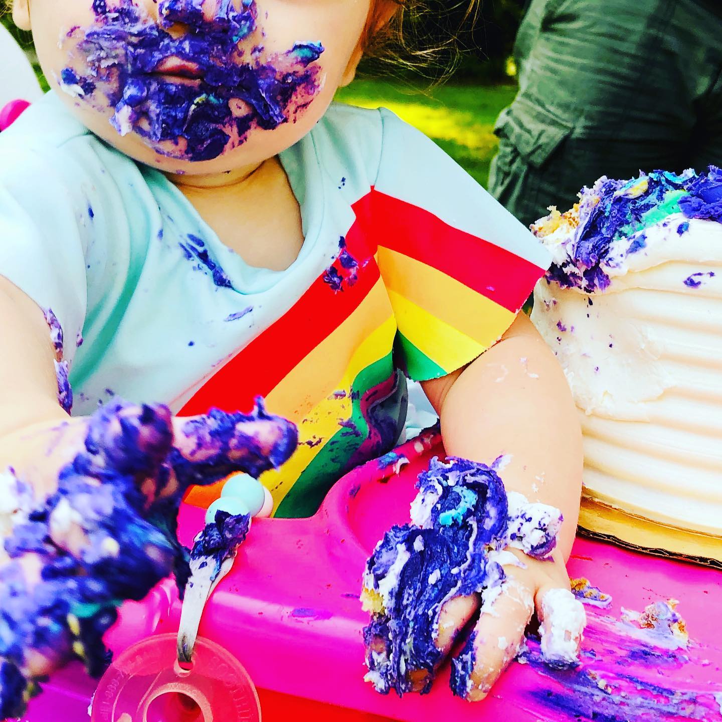 A baby covered in purple frosting from their first birthday cake. Photo by Instagram user @sensorytotspot.