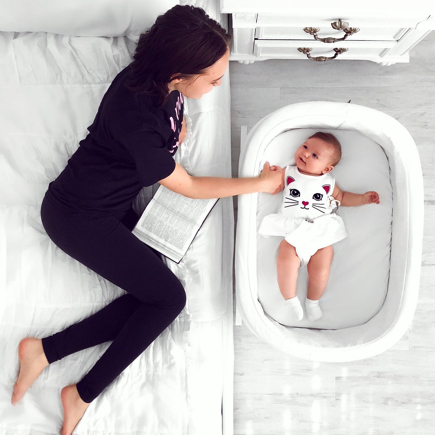 A mother bonding with a baby in a crib. Photo by Instagram user @vicolsfamily.