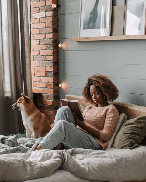 A woman relaxing in bed with a book and her small dog. Photo by Instagram user @sleepwatchapp. 