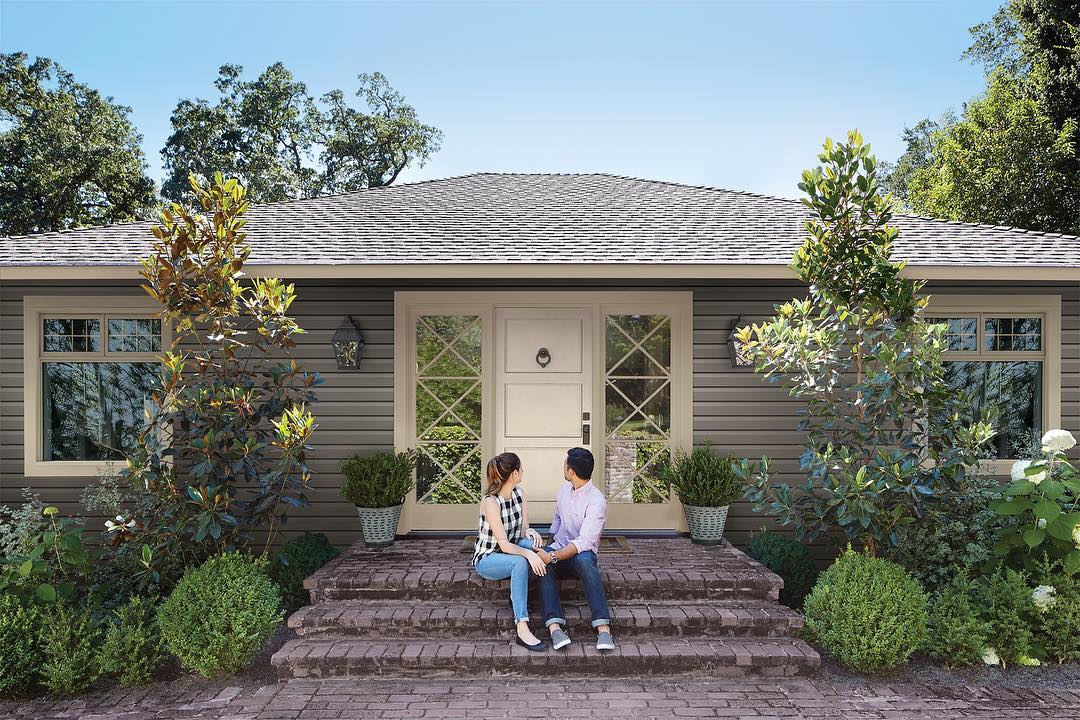 Young couple sitting outside house on porch. Photo by Instagram user @royalbuildingproducts