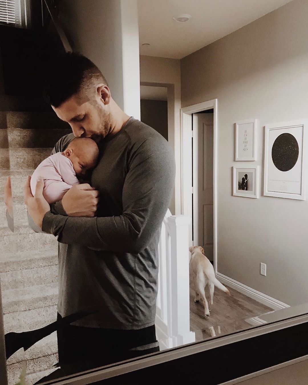 Dad holding newborn baby at home. Photo by Instagram user @littlesleepies