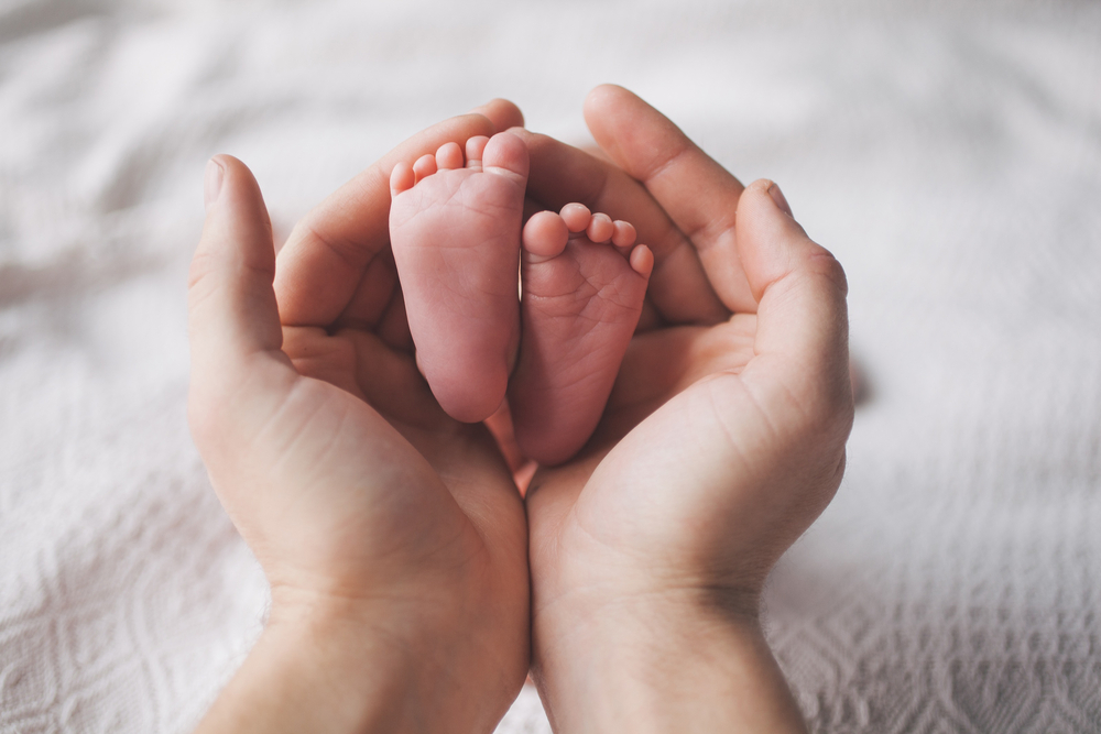 Mother's hands holding newborn baby's feet