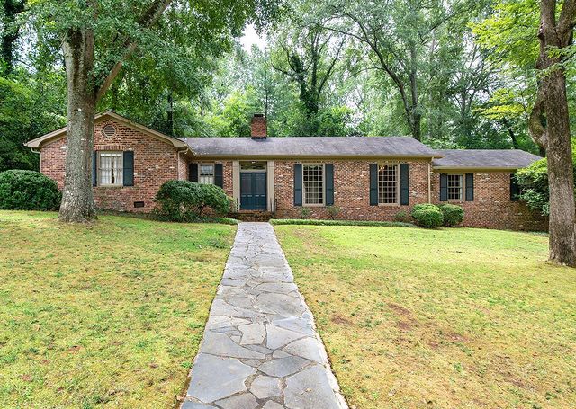 Ranch-style brick home with green lawn and sidewalk leading to front door in Five Points, Denver