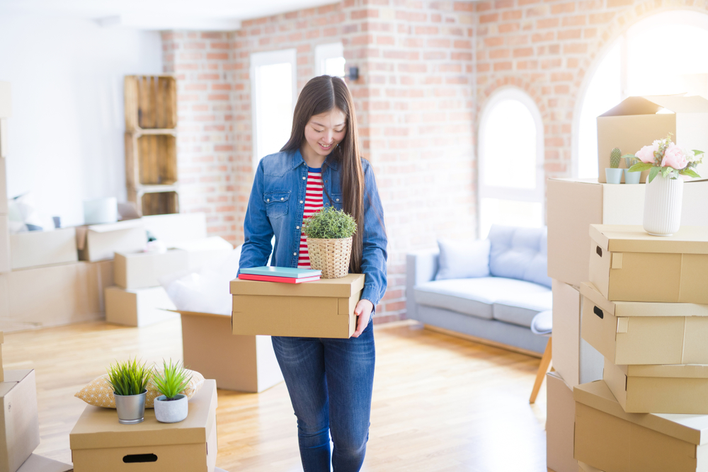 Young woman carrying boxes in new apartment