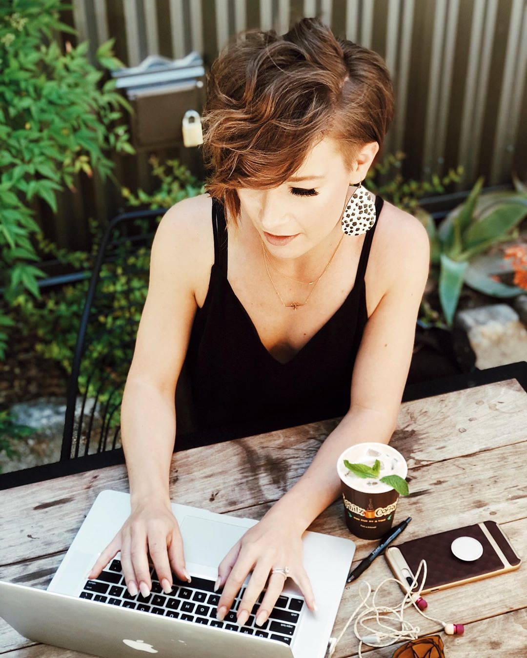 Young woman typing on laptop outside. Photo by Instagram user @kaitlynn.guzman