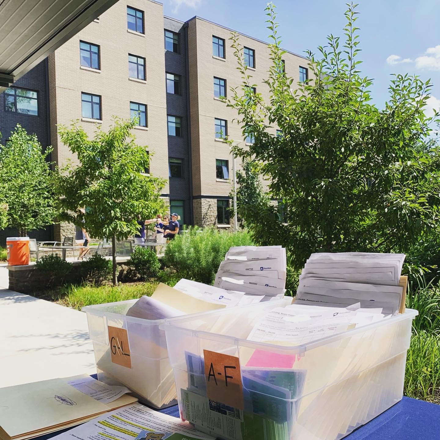 Two containers of documents sit on a blue welcome table for freshman orientation at Penn State University. Photo via Instagram user @lindseewood