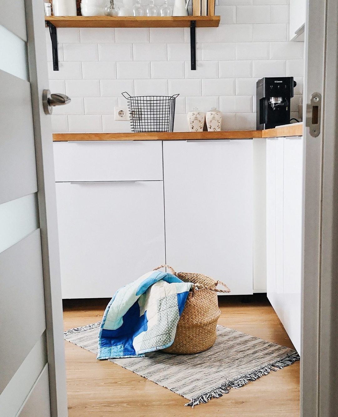 A wicker laundry basket with clothes spilling out in a clean, well-lit kitchen. Photo via Instagram user @healthandwellnessjournal