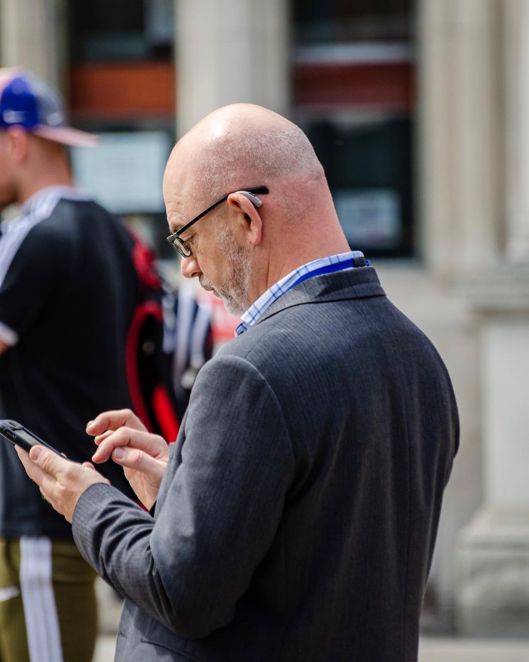 A man uses his phone on the sidewalk of a busy street. Photo via Instagram user @frankson_photography