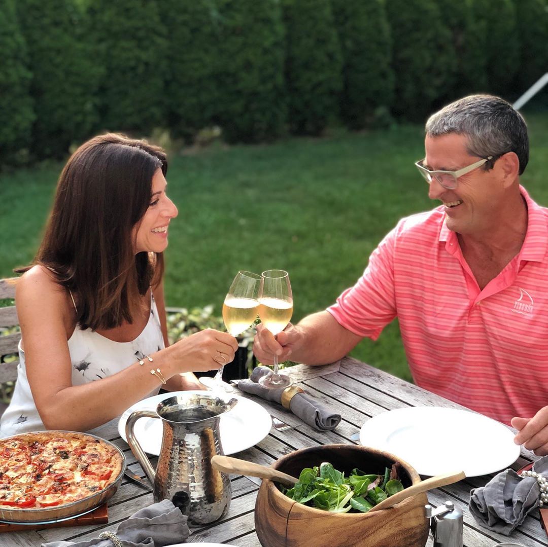 Husband and wife cheersing wine at outside dinner. Photo by Instagram user @caterina.defalco