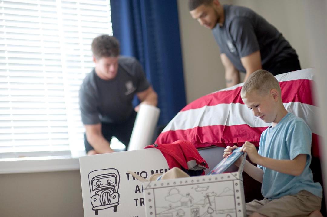 Professional movers helping young boy with his moving boxes. Photo by Instagram user @twomenandatruck
