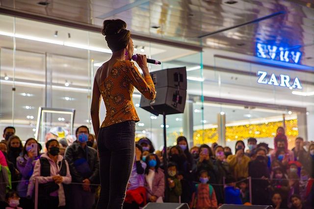 Performer in front of a crowd holding a microphone. Instagram photo by user @hudsonyards