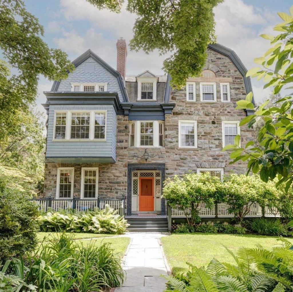 Cottage Style stone home with orange door in Chestnut Hill. Photo via Instagram user @phillysfinesthomes